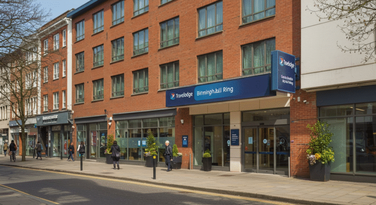 Front view of Travelodge Birmingham Central Bull Ring hotel exterior on a sunny day, showing entrance, signage, and people walking on the street.